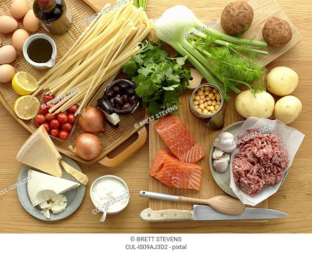 Selection of fresh raw foods with eggs, pasta, herbs, cheese, vegetables, salmon and minced pork