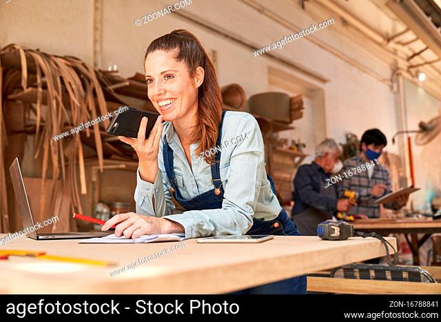 Handwerker Frau am Telefon im Kundengespräch in der Schreinerei Werkstatt