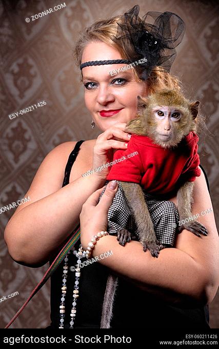 Retro female portrait in the style of 20s or 30s. A gorgeous lady is holding a little monkey