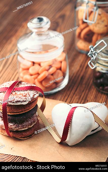 Gingerbread cookies, candies, cakes, sweets in jars on wooden table. Portrait orientation