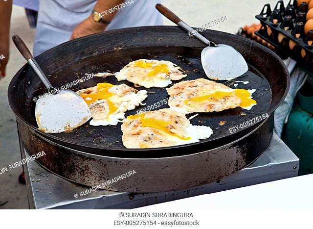 Oysters fried in egg batter being cooked in a pan