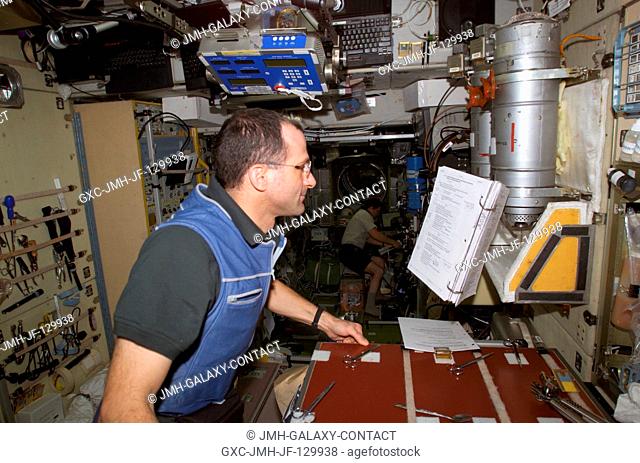 Astronaut Donald R. Pettit, Expedition Six NASA ISS science officer, looks over a procedures checklist in the Zvezda Service Module (SM) on the International...