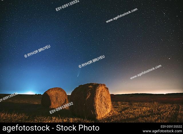 Comet Neowise C2020 F3 In Night Starry Sky Above Haystacks In Summer Agricultural Field. Night Stars Above Rural Landscape With Hay Bales After Harvest