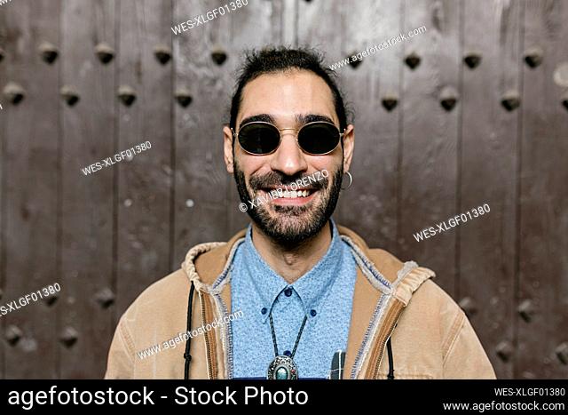 Smiling hipster man standing in front of door