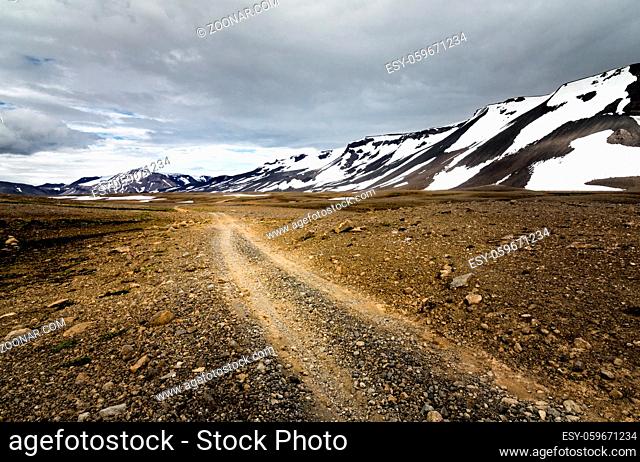 Dramatic scenery of icelandic dirt road towards mountains of Porisdalur. Moody sky above Kaldidalur area in the Highland of Iceland