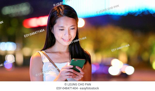 Asian Woman use of app on cellphone in city at night