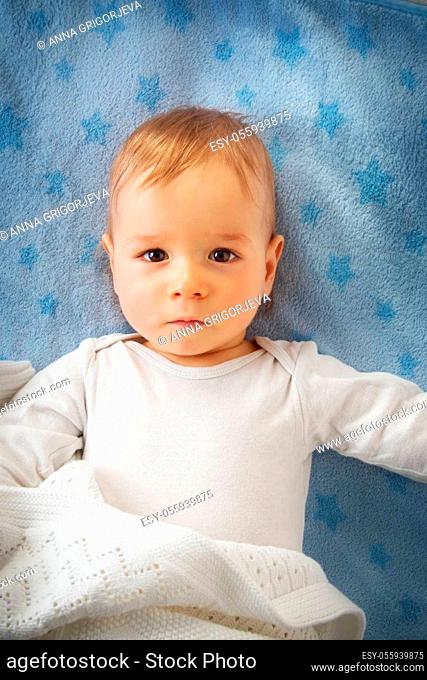 One year old baby lying on blue towel with stars