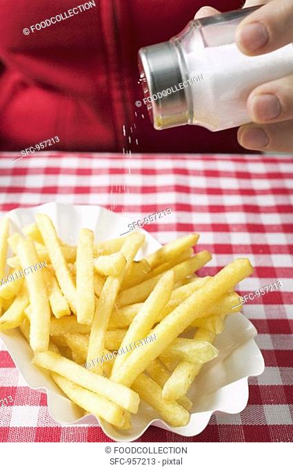 Hand sprinkling salt on chips