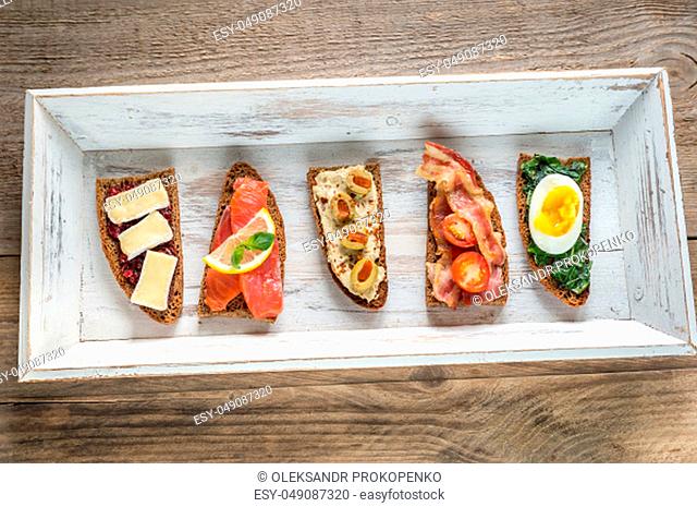 Bruschetta with different toppings on the wooden tray