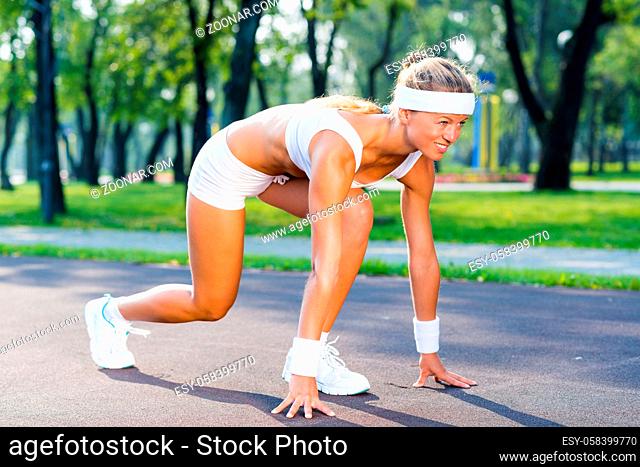 Young woman runner outdoor standing in start pose