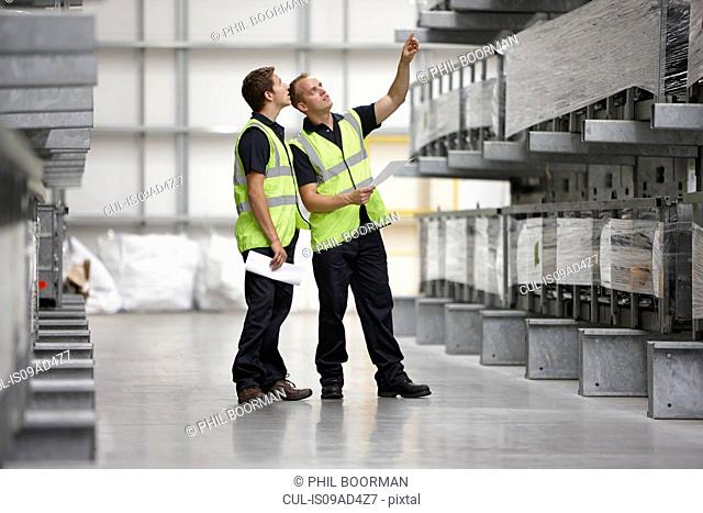 Warehouse workers checking shelves in engineering warehouse