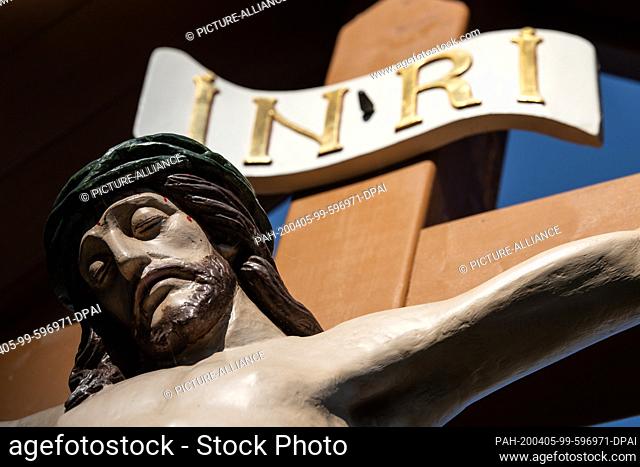 05 April 2020, Thuringia, Heiligenstadt: A Jesus figure with the writing ""INRI"" is attached to a cross at the St. Aegidien church