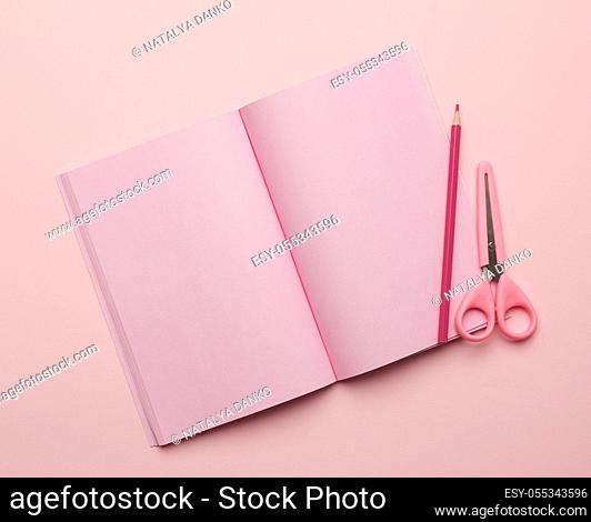 open notepad with blank pink sheets, scissors on pink background, top view