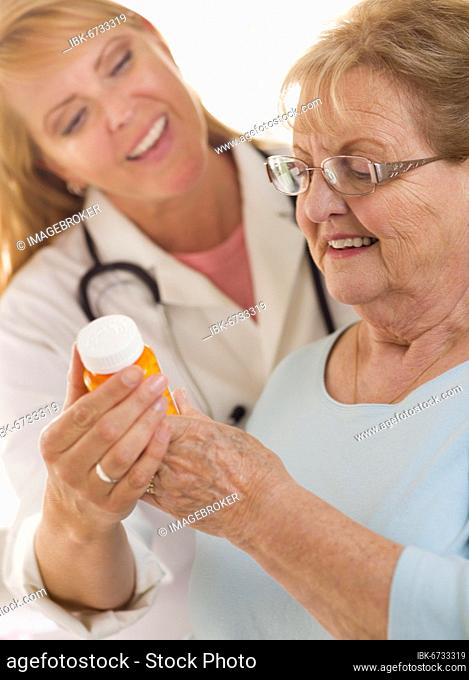 Happy female doctor or nurse explaining prescription to senior adult woman