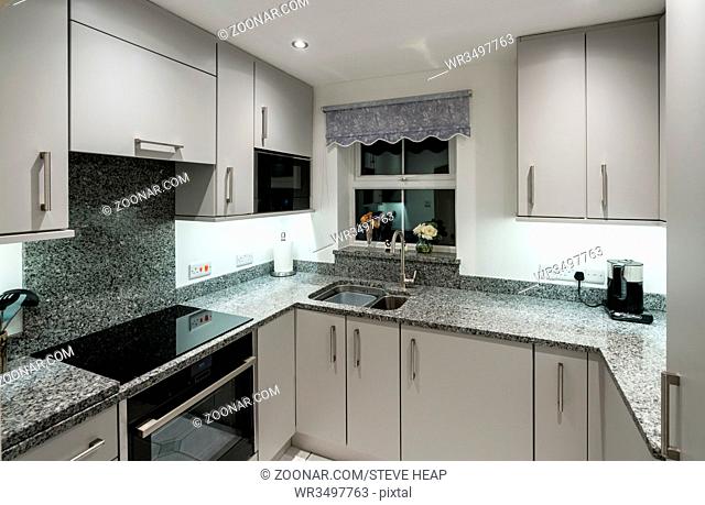 Small modern kitchen in UK apartment with granite and new appliances including induction cooktop