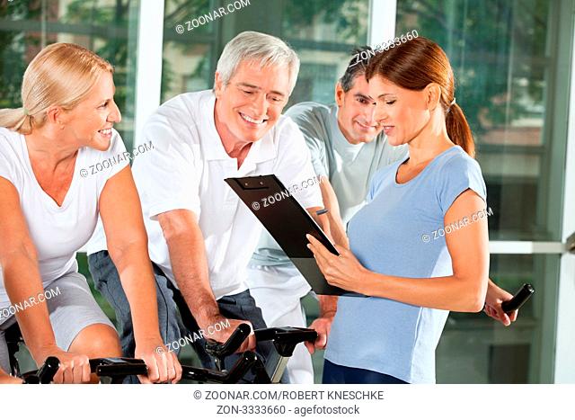 Fitnesstrainierin mit Senioren im Fitnesscenter erstellt Trainingsplan