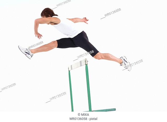 Young man jumping hurdle