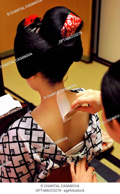 A MAIKO APPRENTICE GEISHA WITH HER TRADITIONAL MAKEUP DORAN. APPLICATION OF A WHITE FOUNDATION SHIRONURI ON HER NECK WITH A BAMBOO BRUSH BURASHI
