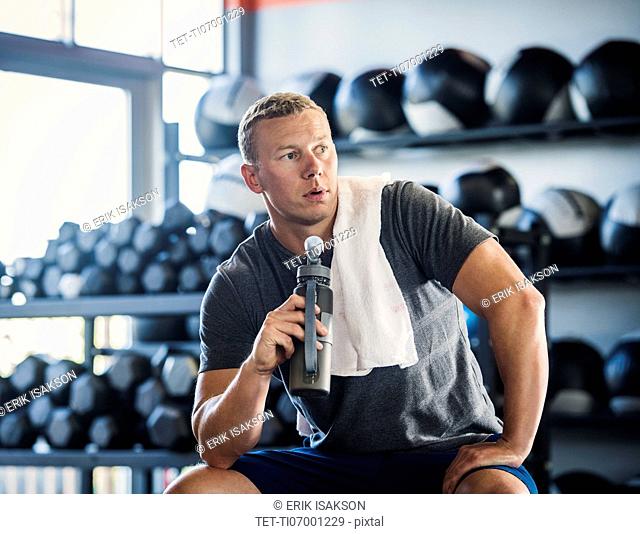 Mid adult man with towel and bottle in gym