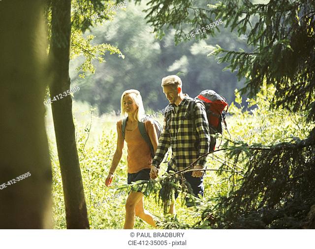 Couple with backpacks hiking in sunny woods