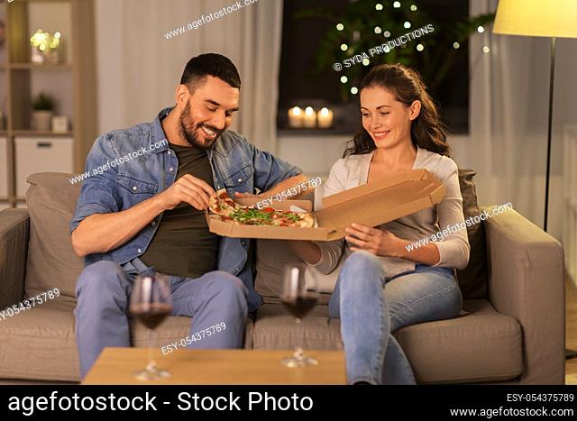 happy couple eating takeaway pizza at home