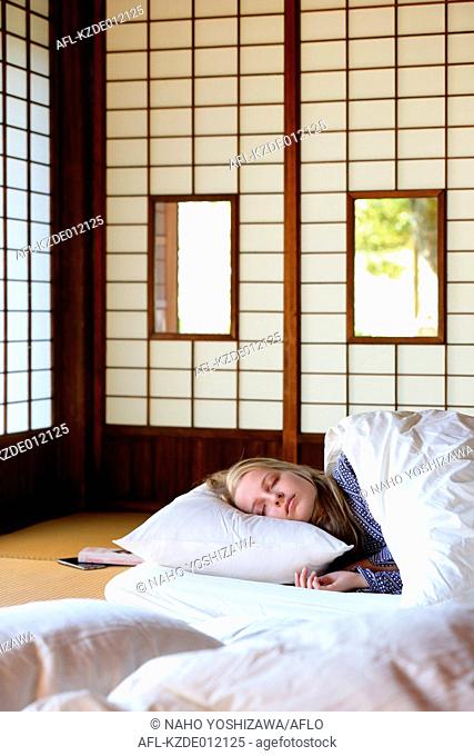 Caucasian woman wearing yukata in traditional Japanese house futon
