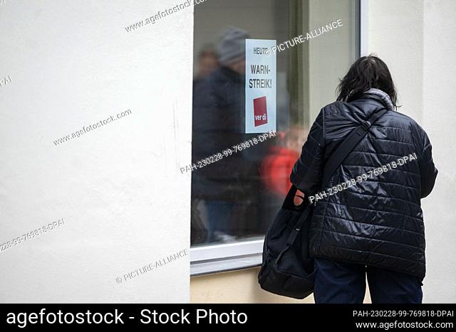28 February 2023, Baden-Württemberg, Tübingen: A woman stands in front of a window of the public library where a poster with the inscription ""Today warning...