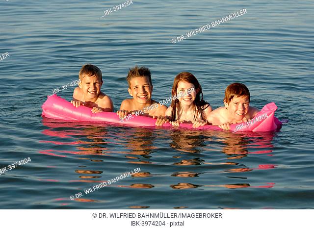 Children on a lilo in the sea, Mediterranean near Fano, Marche, Adriatic, Italy