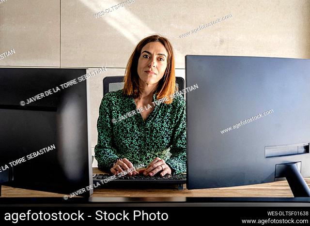 Female entrepreneur with computer sitting at desk in office