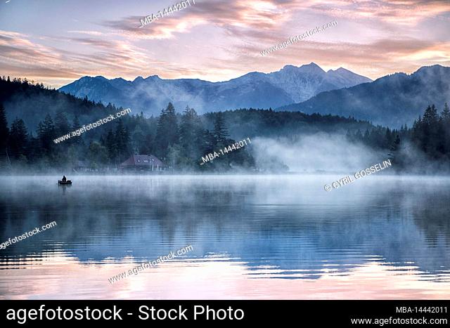 Karwendel and reflection in Lautersee with fishing boat, Mittenwald, Bavaria, Germany