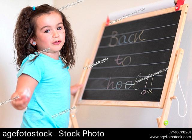 Cute little schoolgirl with chalkboard with text back to school
