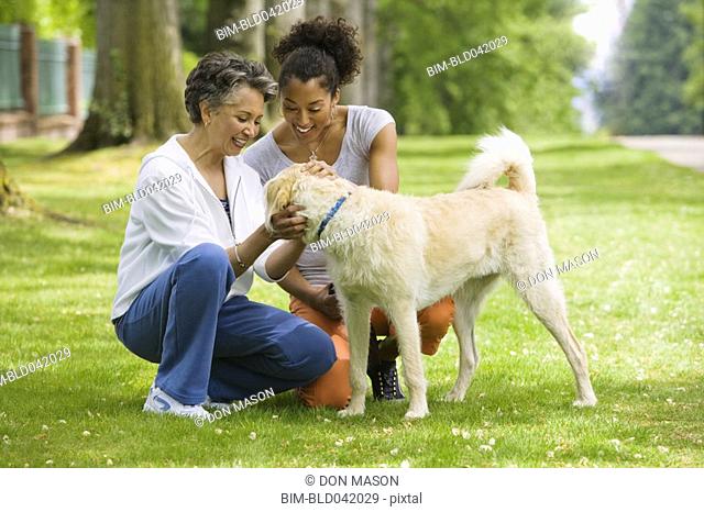 African American mother and adult daughter petting dog