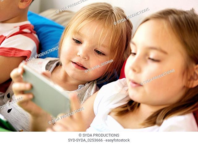 little kids with smartphone in bed at home