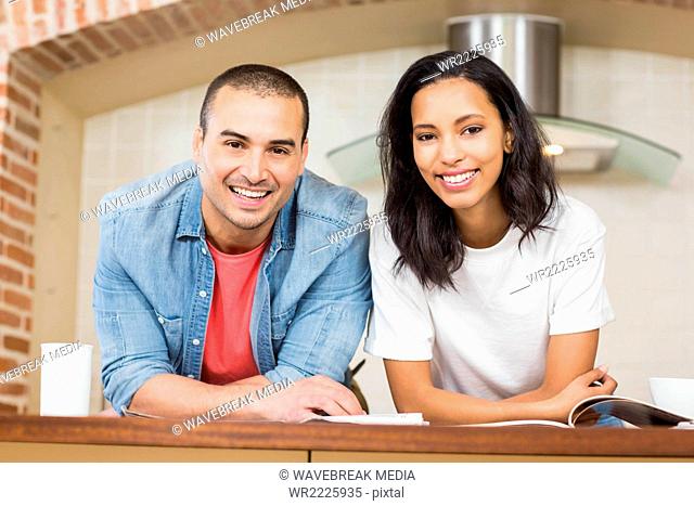 Smiling couple reading newspaper while eating cereals