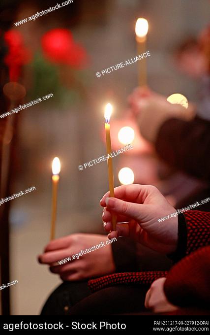 17 December 2023, Saxony-Anhalt, Halberstadt: Participants in an ecumenical service in St. Sixtus and St. Stephen's Cathedral hold candles symbolizing the Light...