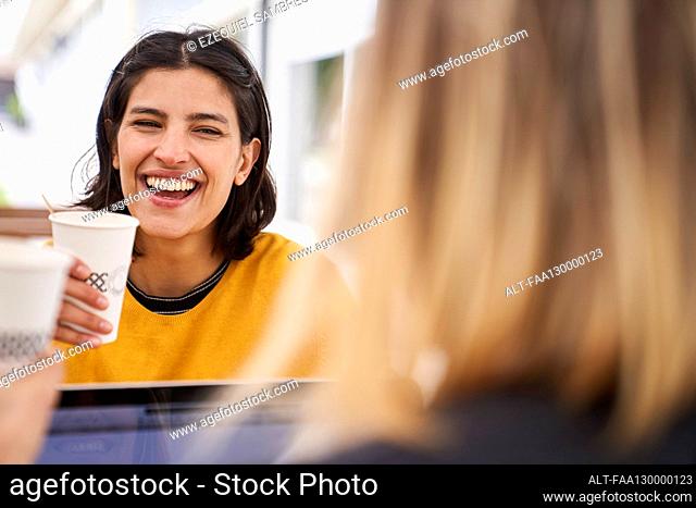 Mid-shot front view of Latin-American businesswoman laughing with her co-worker