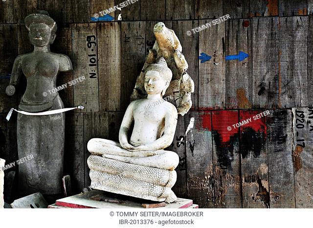 Old Buddha statue and female torso of a deity made of stone in front of a wooden wall, Cambodia, Southeast Asia, Asia