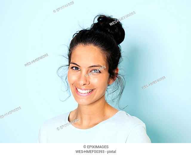 Portrait of young woman with black hair, light blue background