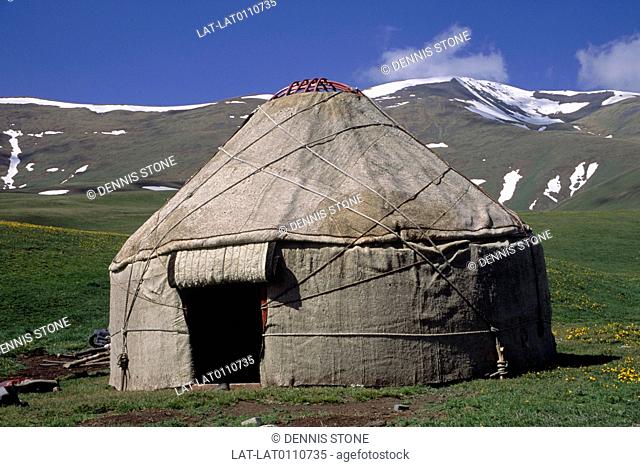 Mountain region. High grasslands. Snow on horizon. Yurt, canvas structure, round tent. Traditional housing for nomadic people