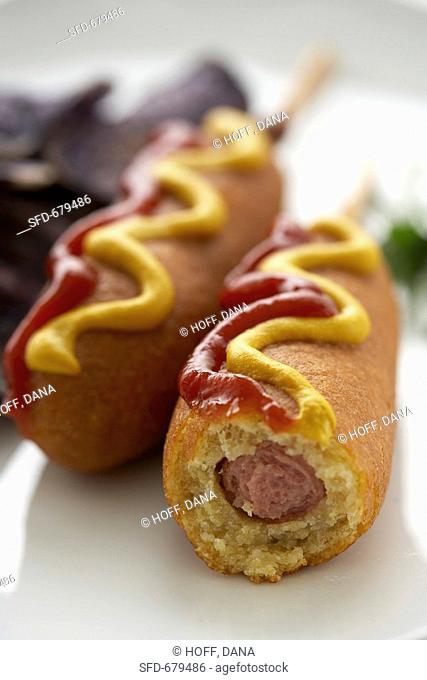 Two Corn Dogs with Mustard and Ketchup, One Bitten