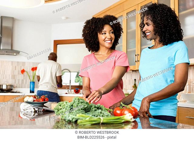 Black women chopping vegetables in kitchen
