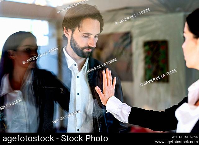 Woman touching man separated through glass pane