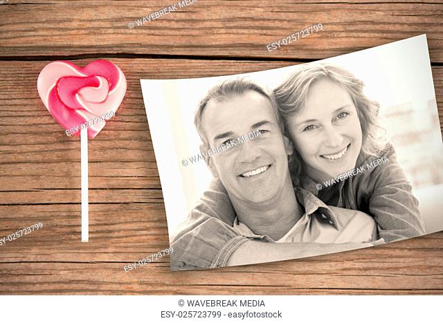 Composite image of smiling woman hugging her husband on the couch from behind