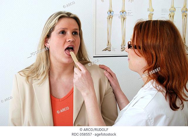 Chubby woman at doctor's, doctor looking in her throat, pharynx, mouth