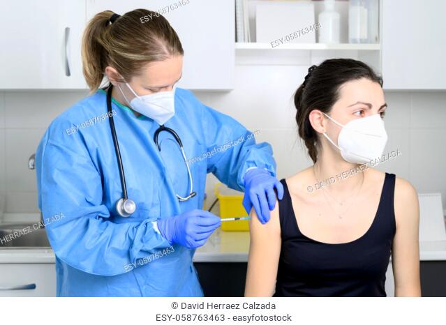 Close up of young woman with protective face mask getting vaccinated, coronavirus concept. High quality photo