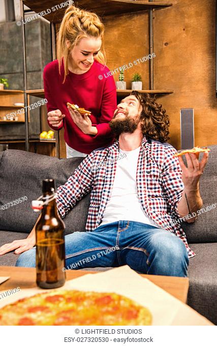 Happy couple with beer and pizza, spending time together at home