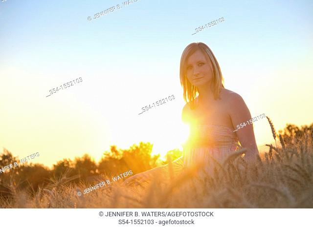 A happy young woman in a field of barley in Lewiston, Idaho, USA