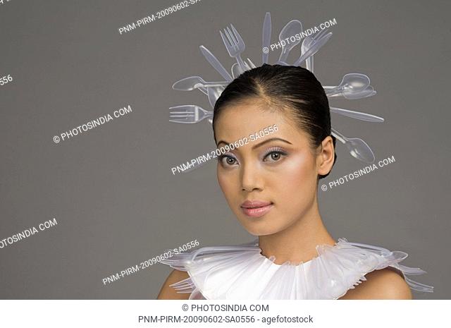 Female fashion model with neck ruff and headwear of plastic forks and spoons
