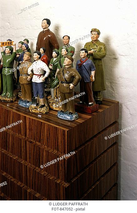 Communist ceramic figurines arranged on a wooden cabinet