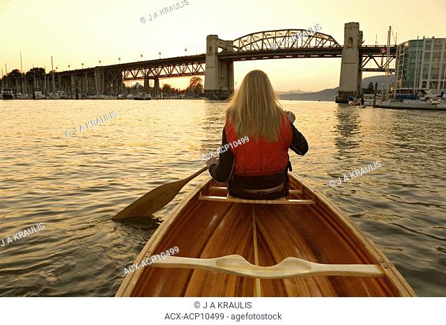 Girl canoeing in False Creek, Burrard Bridge at sunset, Vancouver, British Columbia, Canada